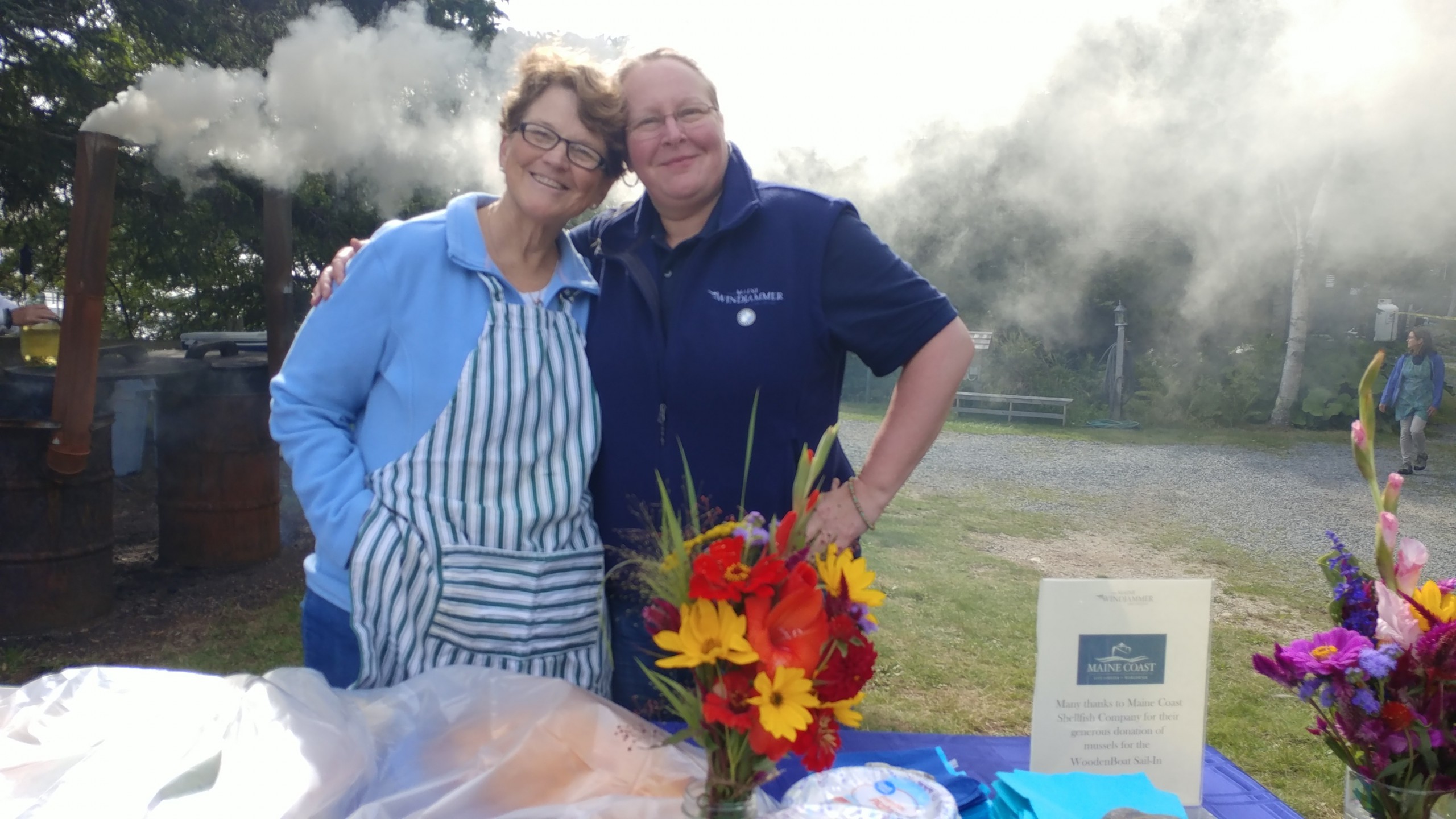 Two women smiling and standing behind the hors d'oeuvres table at WoodenBoat Sail-In